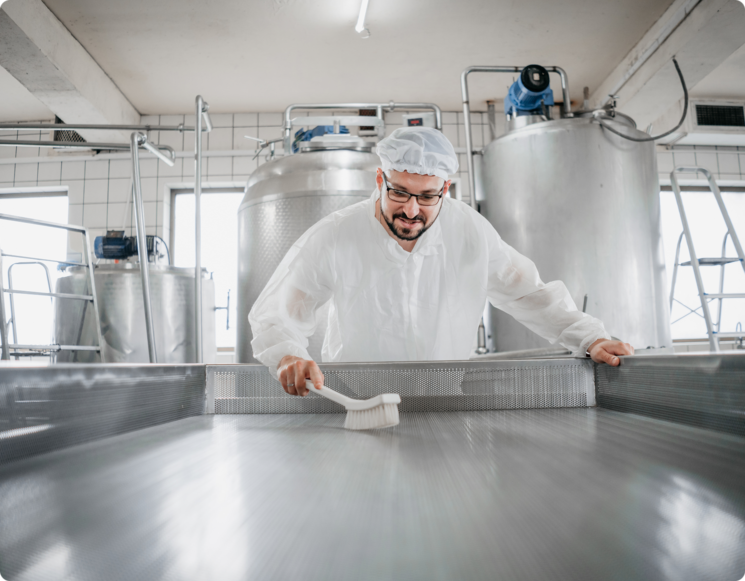 Man cleaning large industrial kitchen surface.